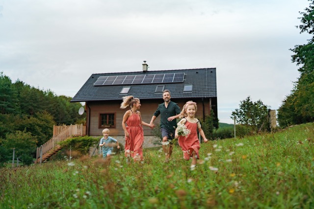 Happy family running near their house with solar panels. Alternative energy, saving resources and sustainable lifestyle concept. installation solaire pour une famille